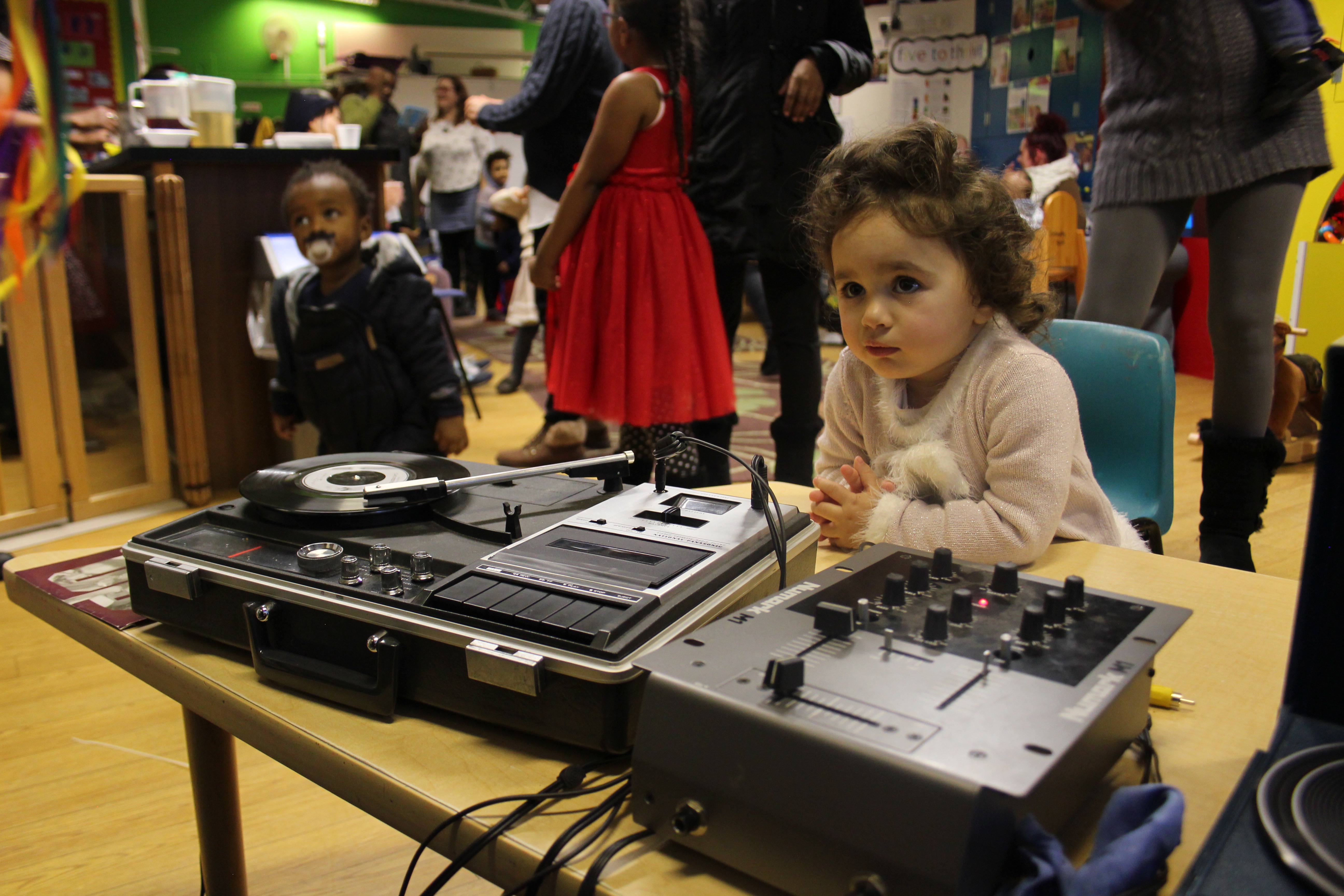 a toddler sits in front of dj decks