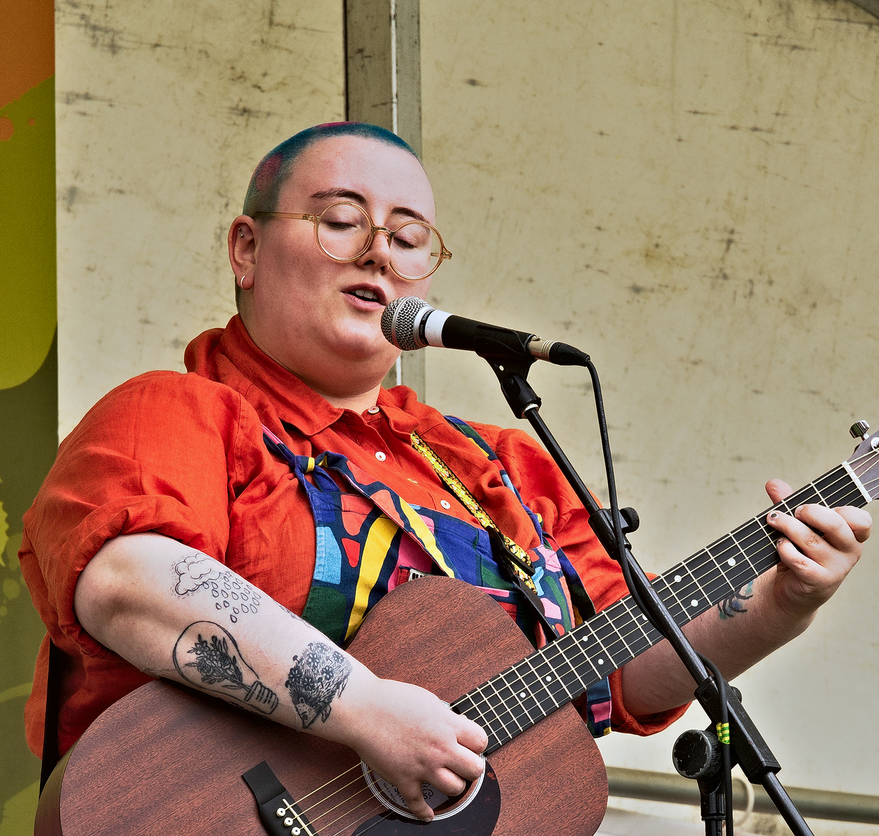 a person with a shaved head plays guitar and sings