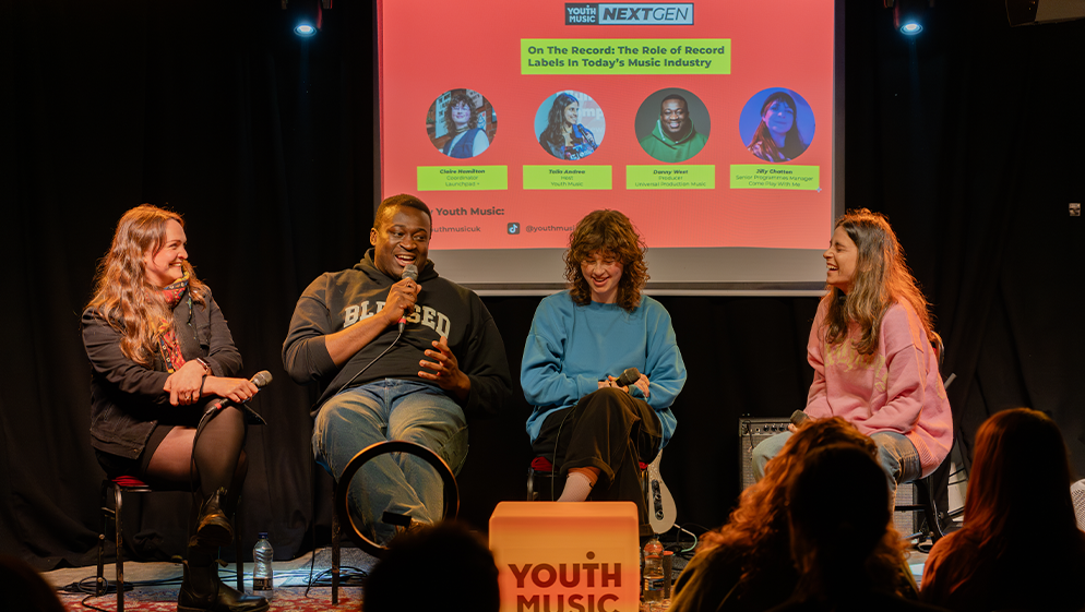 a panel takes place on stage, watched by an audience