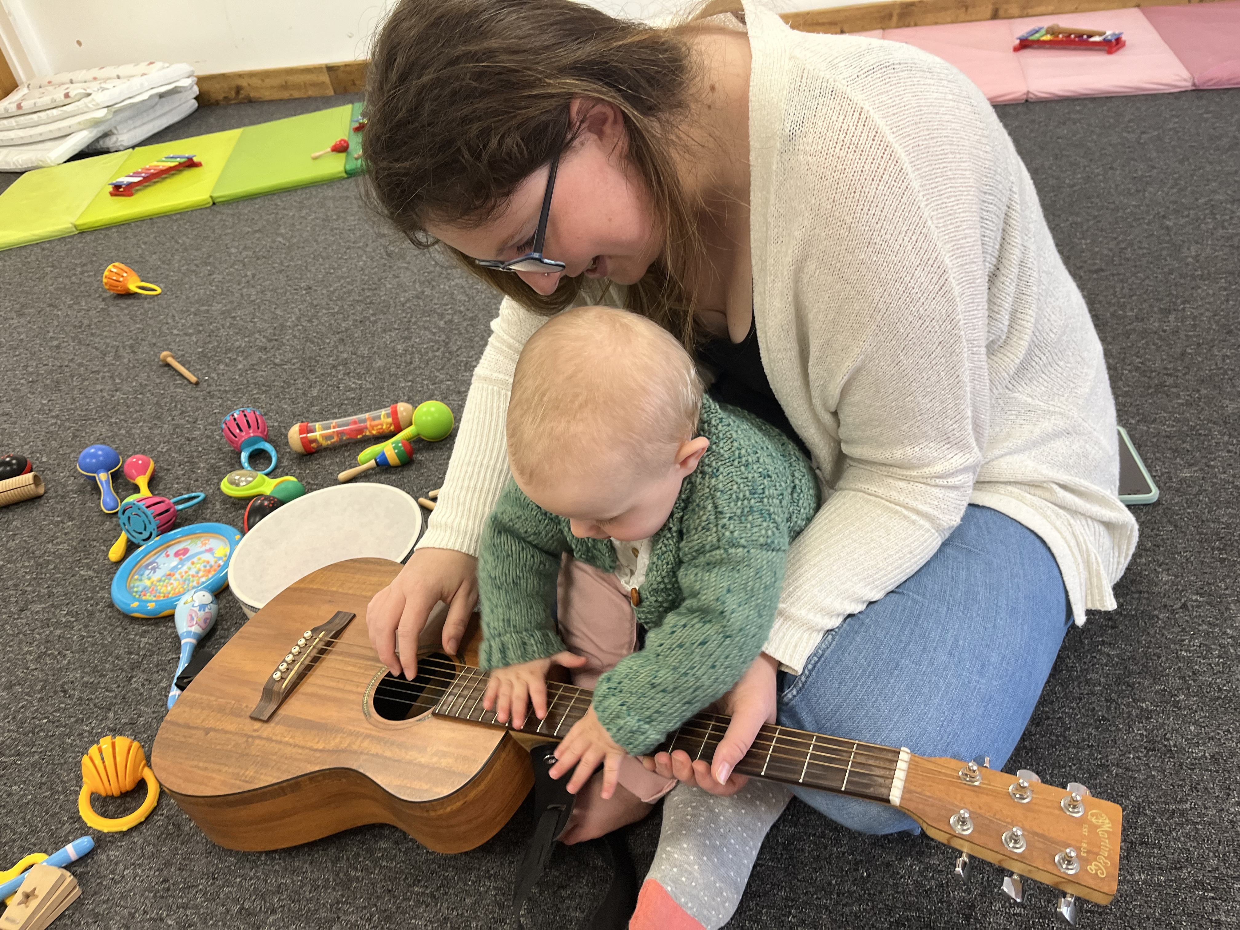 a woman and baby play with an instrument