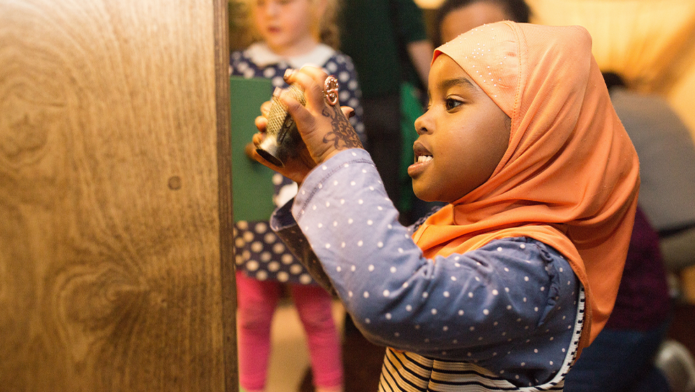 a child wearing a hijab plays with an object