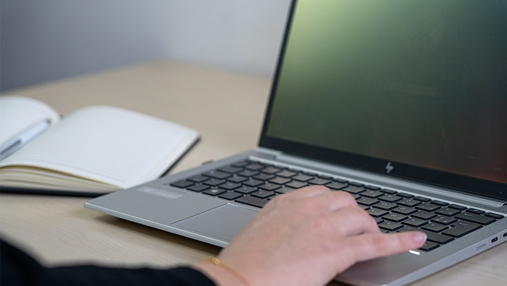 a hand types on a laptop