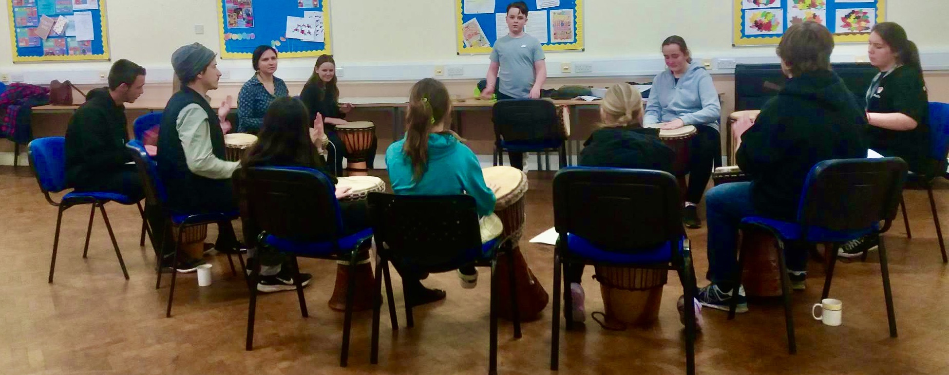 a group of children play drums while seated in a circle