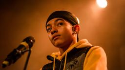 Young person wearing a yellow hoodie and black durag.