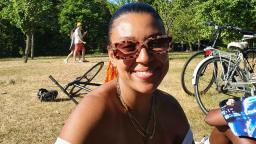 Photo of Jodie sitting in the park wearing sunglasses, visible from shoulders up