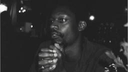 black and white photo of a man sitting with hands together