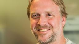 headshot of man with blonde hair and a beard smiling