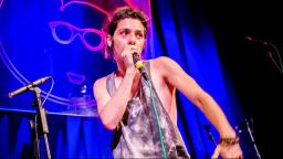 Performer on stage wearing vest and holding mic