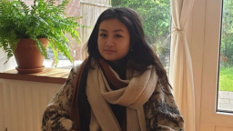 Woman wearing cream scarf sitting in front of fern