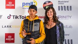 two people standing in front of white board with logos, one holding an award