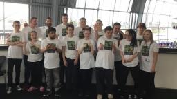 Large group of young people wearing matching white t-shirts with square design