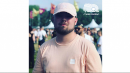 Man at a music festival wearing white cap and peach top