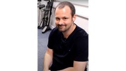 man in black tshirt smiling into camera