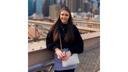 young person leaning against railing of a bridge, city landscape in the background