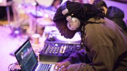 woman wearing headphones producing music on a laptop