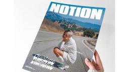 photo of a hand holding Notion Magazine, a women kneeling down on a road is on thefront cover