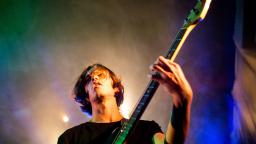 young person playing guitar on stage