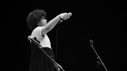 young man with afro holds out a microphone