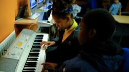 two children play the keyboard together in a music class