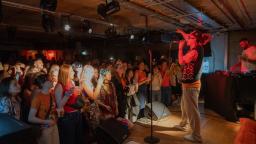 jordan stephens holds a microphone, stands on stage and points into the crowd