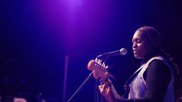 A performer on stage playing the electric guitar and singing into a microphone