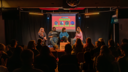 a panel takes place on stage, watched by an audience