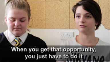 two teenagers in school uniforms with a caption at the bottom third of the screen