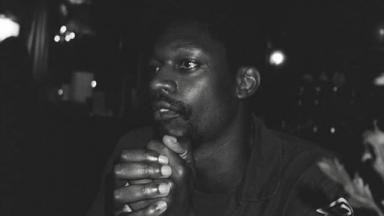 black and white photo of a man sitting with hands together