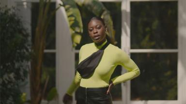 person wearing lime green top and black bumbag in front of glass windows