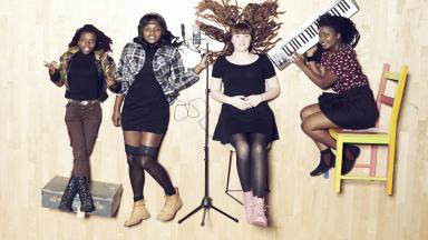 Four young women holding instruments lying on the floor