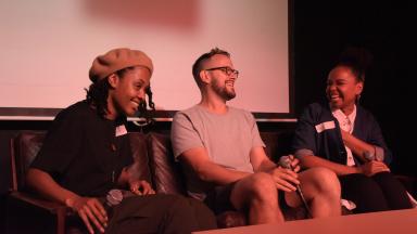 Three people sitting in chairs, chatting and laughing