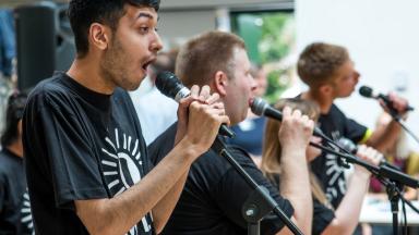 Four musicians singing into microphones