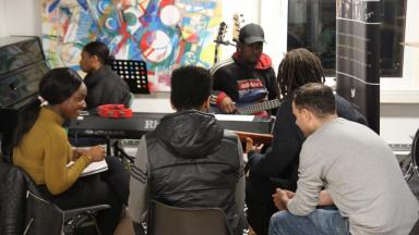 six people sitting around a table looking at various bits of paper together