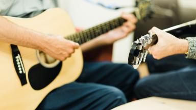 two people playing guitars, only the guitars and their hands are visible