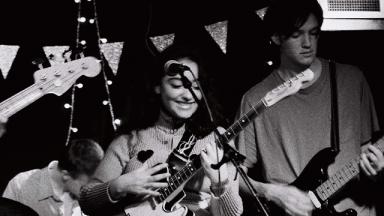 black and white photo of a young woman playing a guitar on stage