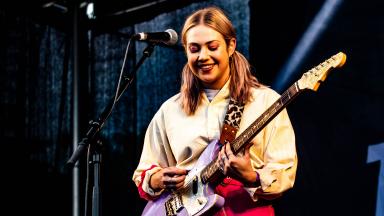 young person playing guitar on stage