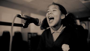 Person with hair in bunches singing into microphone