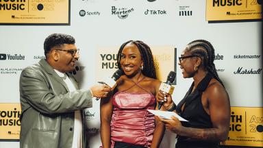 two presenters hold microphones to interview an award winner