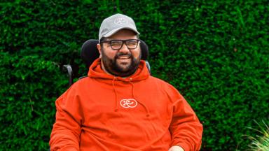 sanjeev mann wears a white cap and a red hoodie