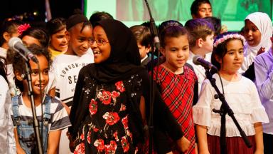 a group of children stand together in a group; some are singing