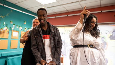 a group of young people laugh and smile as they stand up and dance to music