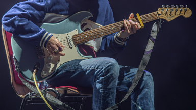 a person sits on a chair and plays electric guitar