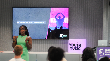 a woman with braids and a green dress stands in front of a screen with the text  