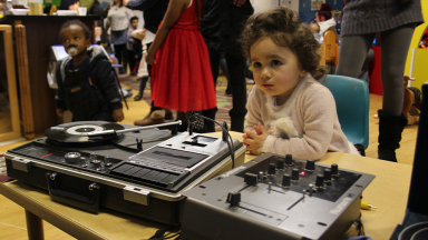 a toddler sits in front of dj decks