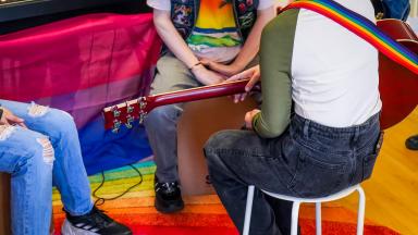 a group of people sit around a colourful room with instruments