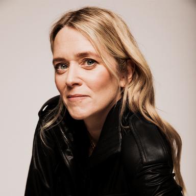 blonde woman wearing black top against a white background