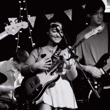 black and white photo of young person playing a guitar on stage