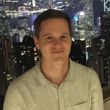 man wearing white shirt with city landscape at night in the background