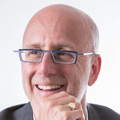 man with glasses smiling against white background