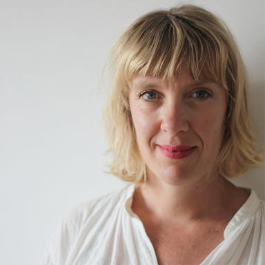 woman with blonde hair and fringe wearing white shirt against a white background